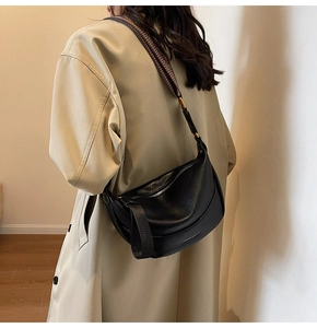 Détail du sac demi-lune noir avec lettrage doré et bandoulière en jacquard réglable