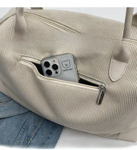 Close-up of beige corduroy travel bag showing detailed texture and rear zipper pocket