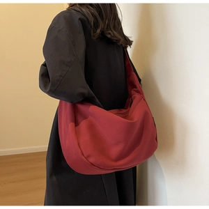Détail du grand sac bandoulière en toile rouge foncé montrant la texture et la forme demi-lune