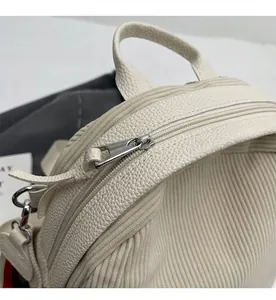 Detail of smooth metal zipper and textured corduroy fabric on a cream shoulder bag