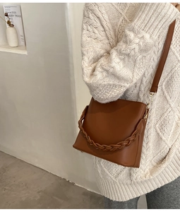 Détail du sac seau en cuir caramel avec anse tressée et bandoulière amovible réglable