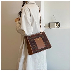 Detail of checkered woolen tote bag with leather trim and gold chain shoulder strap