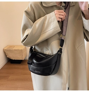 Détail d'un sac bandoulière demi-lune noir avec large sangle et lettrage doré