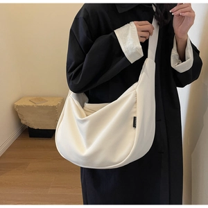 Détail de la texture en velours côtelé crème et large bandoulière du sac besace