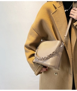 Détail du sac seau beige avec poignée tressée épaisse et accents métalliques dorés