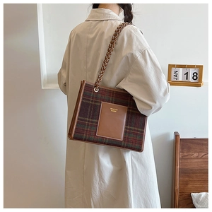 Detail of tartan wool tote bag featuring a leather pocket and chain shoulder strap