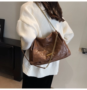 Détail du sac hobo matelassé marron avec chaîne dorée et pull en maille blanc