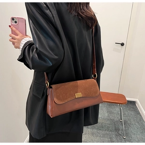 Detail of vintage matte suede shoulder bag with gold clasp shown on a model
