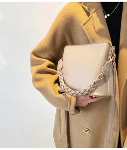 Vue détaillée du sac seau en cuir beige avec poignée tressée sur une épaule de mannequin