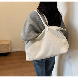 Close-up of large corduroy tote bag with reinforced leather corners on model