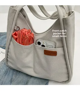 Close-up of canvas tote bag front pockets holding a foldable umbrella and phone