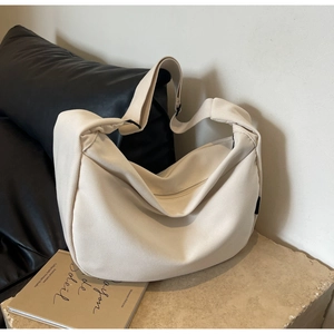 Détail du sac bandoulière en toile blanc cassé montrant la texture durable du tissu