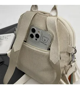 Detail of corduroy backpack showing the front zipper pocket and internal storage capacity