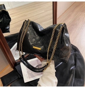 Détail du sac à main matelassé en cuir verni noir avec boucle dorée et bandoulière