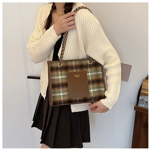 Detail of tweed checkered tote bag showing gold chain strap and textured fabric