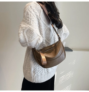 Détail d'un sac demi-lune marron foncé avec texture cuir et bandoulière tressée chic