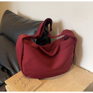 Détail du sac bandoulière en toile rouge foncé avec large sangle réglable et zip noir