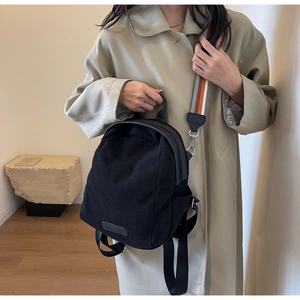 Detail of black corduroy mini backpack with vibrant orange blue striped wide shoulder strap