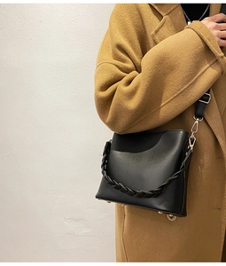 Détail de la poignée tressée et des pieds en métal doré sur un sac seau noir