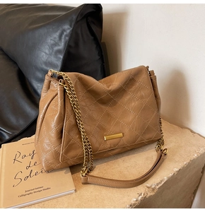 Détail du sac matelassé marron avec bandoulière chaîne dorée et plaque en métal poli