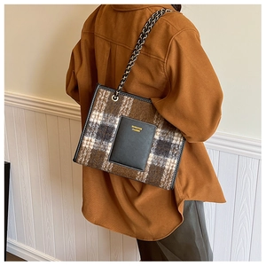 Detail of wool tote bag featuring brown plaid pattern and gold branded leather pocket