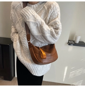 Détail d'un sac demi-lune marron avec bandoulière à chevrons et texte logo doré