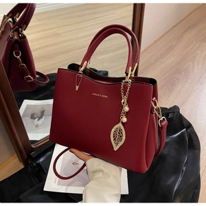 Macro view of burgundy red faux leather wedding bag with gold leaf and pearl pendant