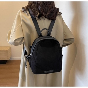 Detail of black corduroy backpack on model showing size and soft textured fabric