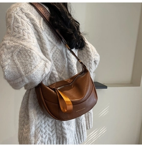 Détail du sac hobo marron avec texte doré et bandoulière tissée porté par un mannequin