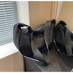 Gros plan détaillé du sac bandoulière croissant noir en toile avec large sangle réglable