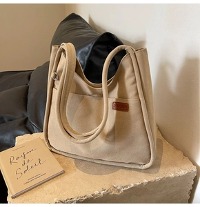 Detail of khaki canvas tote bag with leather logo and metal ring on stone base