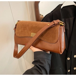Detail of caramel brown underarm bag showing matte suede and smooth leather texture