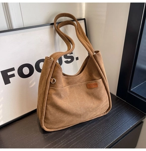 Close-up of brown suede-texture canvas tote bag with front pocket and metal D-ring detail