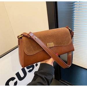 Detail of brown contrast suede and leather crossbody bag with brushed gold lock hardware