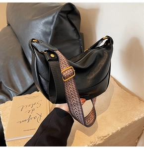 Détail d'un sac demi-lune noir avec bandoulière en jacquard tissé et ferrures dorées vintage