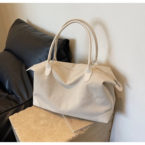 Detail of beige corduroy tote bag showing ribbed texture and leather corner reinforcements