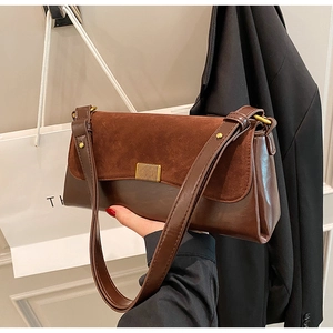 Close-up of vintage brown suede shoulder bag featuring a decorative vertical gold buckle
