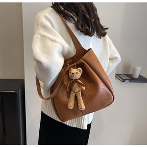 Detailed view of brown lychee grain leather bucket bag with a cute bear charm accessory