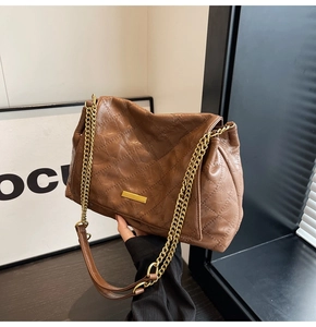 Détail de la texture cuir matelassé marron et plaque dorée sur le sac à chaîne minimaliste