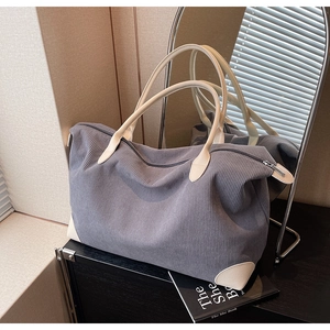 Detail of the high-capacity grey corduroy handbag with cream leather handles and texture