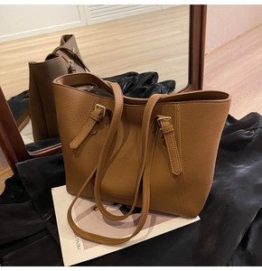 Détail du sac cabas en cuir litchi caramel avec boucles dorées et logo imprimé