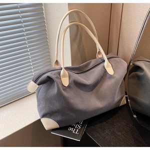 Close-up of grey corduroy shoulder bag with reinforced beige corners and zipper detail