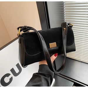 Detail of black underarm bag featuring suede patchwork and gold rectangular buckle