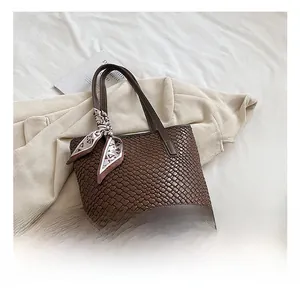 Detail shot of brown woven leather tote with geometric silk scarf and texture