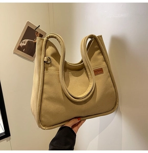 Close-up of khaki canvas tote bag with front pockets and leather logo detailing