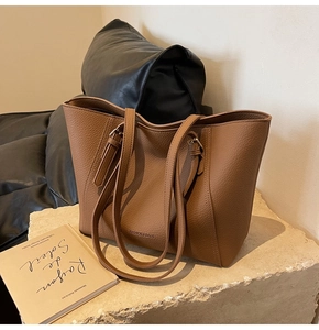 Détail d'un sac cabas marron en cuir grainé avec boucles métalliques et logo chic