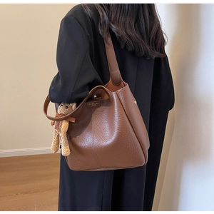 Detail of a large brown pebble leather bucket bag with a cute teddy bear charm on the strap