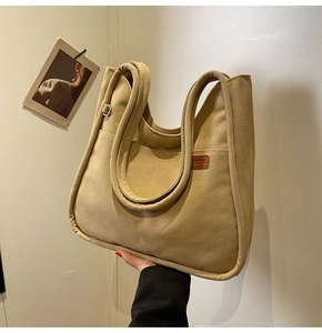 Detail of khaki canvas bucket bag with silver metal ring and brown leather patch