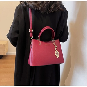 Detail of red wedding handbag featuring textured vegan leather and a gold leaf charm