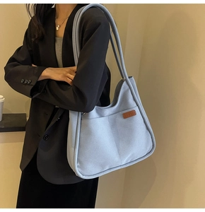 Detailed side view of light blue large canvas tote bag with front pockets and leather tag